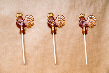 sugar lollipop roosters on wooden paper