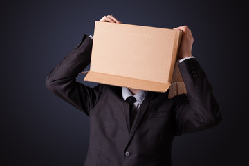 Businessman gesturing with a cardboard box on his head