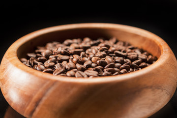 Closeup of Wooden Bowl Filled with Brown Coffee Beans. Over Blac