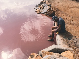 Man looks at pink water of Torrevieja lake and thinks