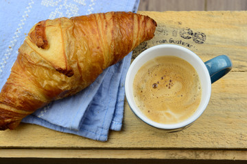 Coffee with croissant on old wooden table