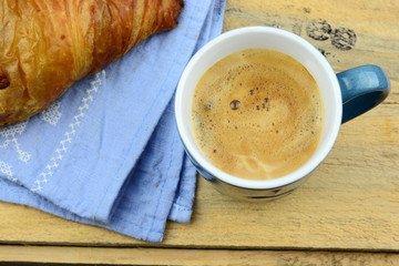 Coffee with croissant on old wooden table