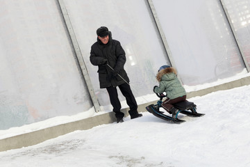 Fototapeta na wymiar Grandfather with grandson on a snowy hill