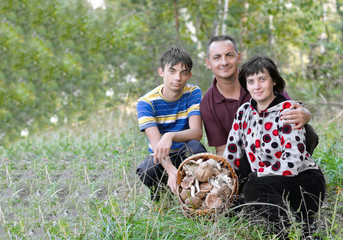 Семья, муж жена и сын, в лесу на поляне с корзиной грибов