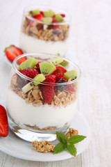 yogurt dessert with muesli and berries in small glass