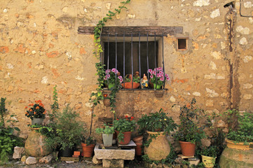 Fototapeta na wymiar window in stone rural house with flower pots, Provence