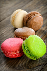 Different kinds of macaroons in stack on wooden background,