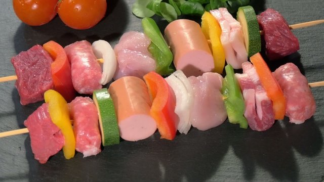 raw meat skewers on stone plate rotating