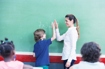 Teacher congratulating with kid in primary classroom