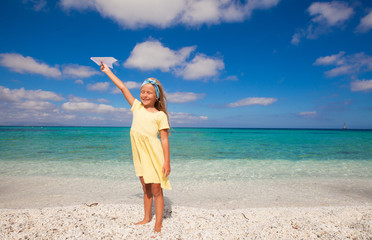 Happy little girl playing with flying kite during tropical beach