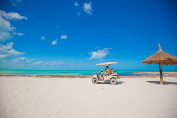Dad and his little girls driving golf cart on tropical beach