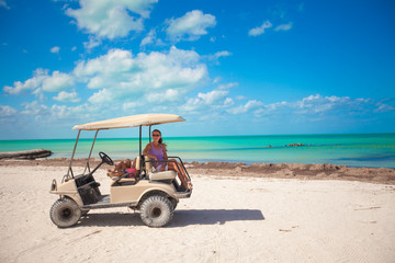 Little girls and their mother driving golf cart at tropical