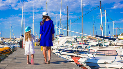 Young mother and little girl in port during summer vacation