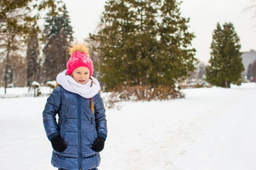 Fototapeta na wymiar Portrait of little happy girl in the snow sunny winter day