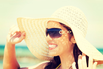 Fototapeta premium Beautiful woman in hat and swimsuit over seaside.