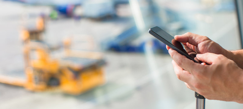 Close up man's hands using cellphone inside airport