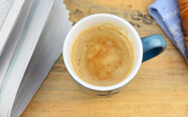 Coffee with croissant on old wooden table and newspaper