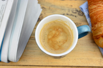 Coffee with croissant on old wooden table and newspaper