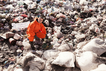 Portrait of recycling worker among garbage bags on the landfill