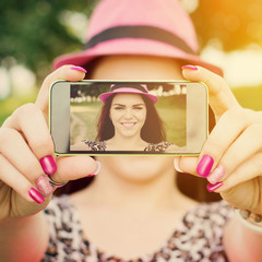Teenage girl taking a selfie in park in summer