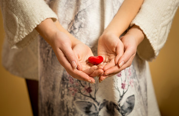 mother and little daughter holding red heart in hands