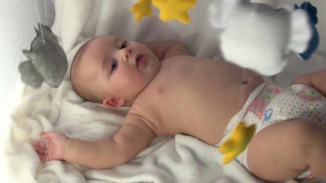 neonato in pannolino con gioco giostra