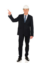 Smiling businessman with hard hat pointing up
