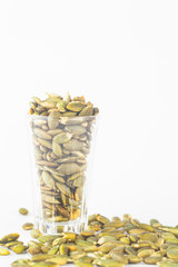 Pumpkin seeds close up in glass on white blackgroud