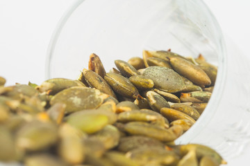 Pumpkin seeds close up in glass on white blackgroud