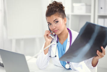 Female doctor looking x-ray scan and talking on phone in