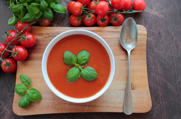 Bowl with tomato cream soup on wooden board
