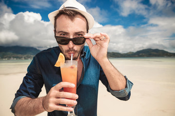 lman on the beach drinking a orange cocktail