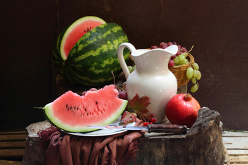 Grapes, a pomegranate, a water-melon and a white jug