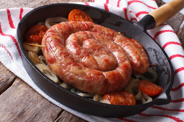 Delicious grilled sausage with onions and tomatoes in a pan