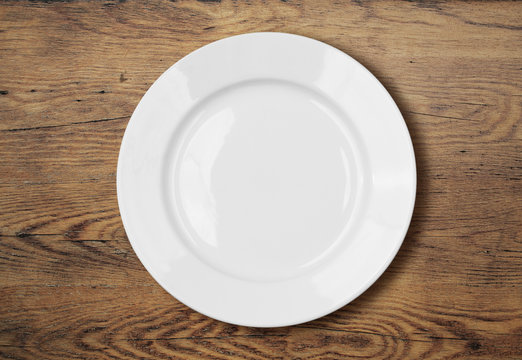 white empty dinner plate on wooden table surface