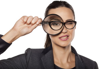 smiling young woman looking through a magnifying glass