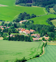 Rural summer landscape with village iv green grass field
