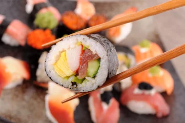 Foto op Plexiglas Futomaki sushi held by chopsticks © jc_studio