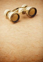 Old binoculars on vintage paper background