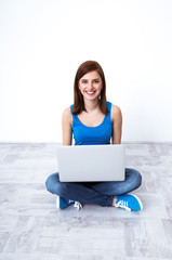 Young smiling woman sitting at the floor with laptop