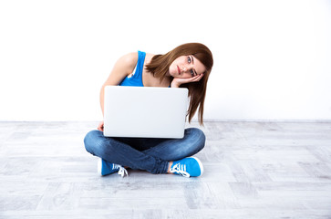 Depressed young woman sitting at the floor with laptop