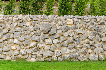 fence real stone wall surface with cement on green grass field - 76310829