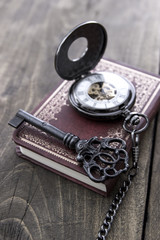 pocket watch and old key on  wooden table