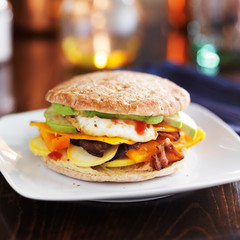 breakfast sandwich with egg, bacon, avocado and vegetables