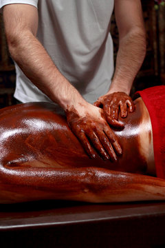 Beautiful young woman getting chocolate massage at spa