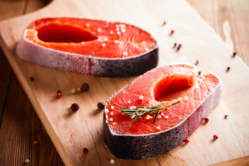 Raw salmon steak on wooden cutting board