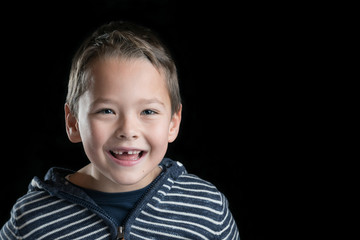 Kind mit Zahnlücke freigestellt vor schwarzem Hintergrund