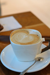 Hot cappuccino in white cup on the wooden table