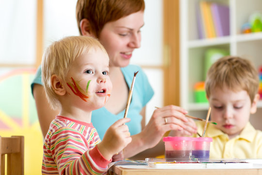 cute mother teach her kids to paint