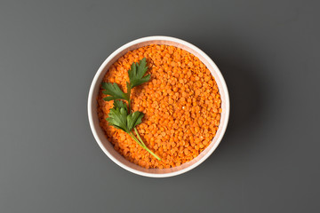 raw red lentils in white bowl on gray background